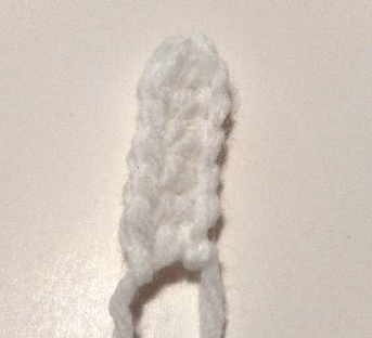 Sewing white crochet petals onto the yellow and green daisy center