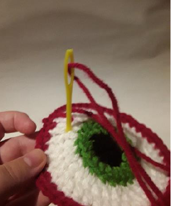 Embroidering a black outline around the blue iris of the crochet eyeball.
