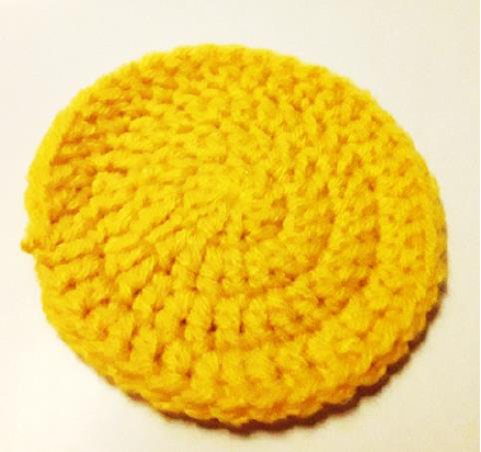 The completed yellow crochet circle for the coaster base.