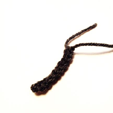Two finished black crochet spider legs, showing their segmented texture