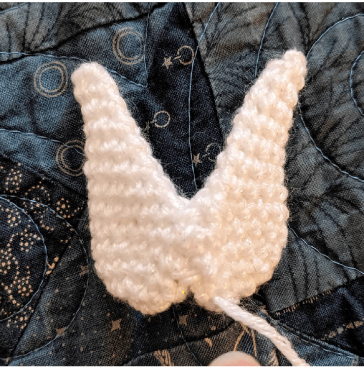 Assembling the crocheted toy: showing placement of legs and arms