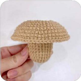 A small, dark brown crocheted circle representing the capybara's nose.