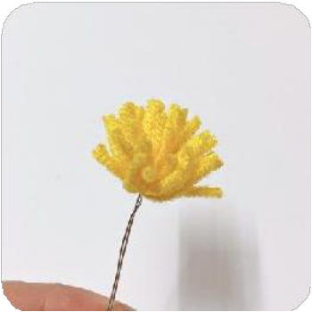A single white crocheted flower being held, showcasing its delicate petals.