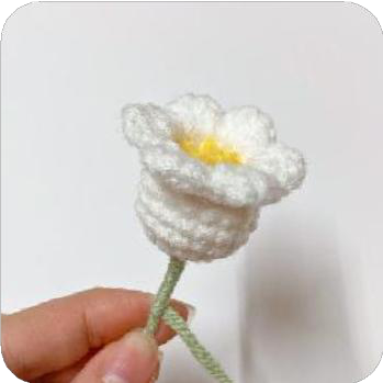 Three crocheted lily flowers arranged on a single green stem, forming a small cluster.
