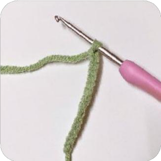 Green yarn attached to a piece of wire, preparing to crochet a leaf.