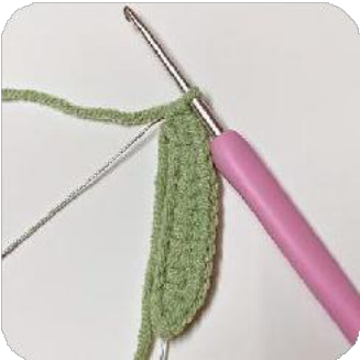 A partially crocheted green leaf showing the stitch pattern around the wire.